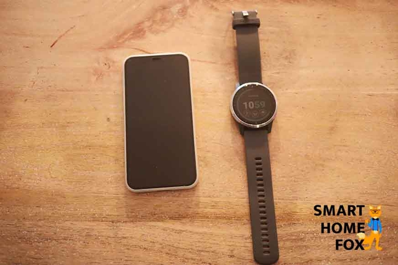 Garmin vivoactive 4 рядом с мобильным телефоном на столе.